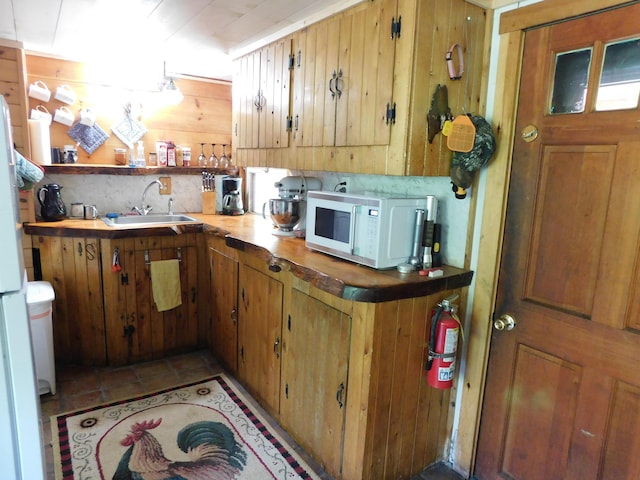51 Pond Rd, Abbot, ME 04406 - kitchen with white microwave, a sink, wooden walls, and brown cabinets