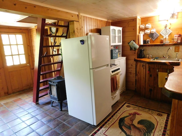 51 Pond Rd, Abbot, ME 04406 - kitchen with white appliances, a sink, wooden walls, open shelves, and a wood stove