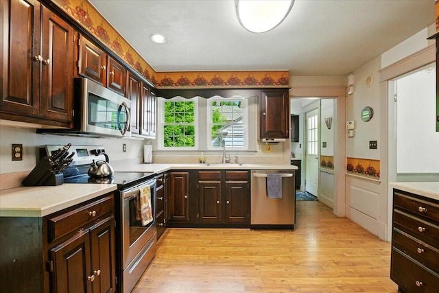 11 Pine Ave, Livermore Falls, ME 04254 - kitchen with stainless steel appliances, light countertops, light wood-style flooring, and wainscoting