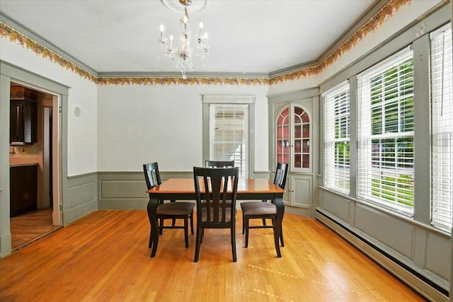 11 Pine Ave, Livermore Falls, ME 04254 - dining space with baseboard heating, light wood finished floors, wainscoting, a chandelier, and a decorative wall
