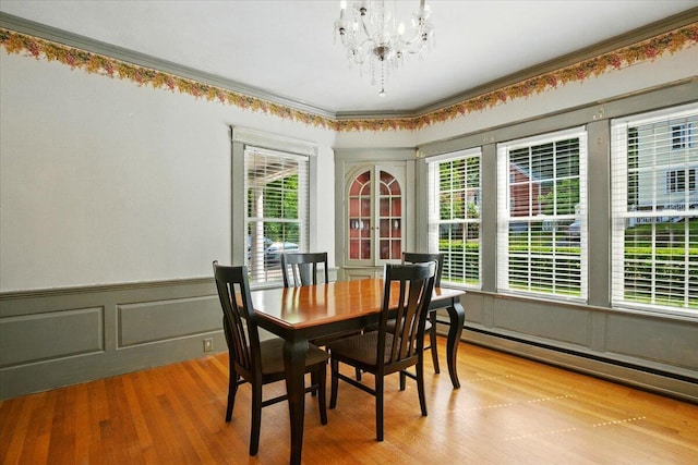 11 Pine Ave, Livermore Falls, ME 04254 - dining space featuring a chandelier, a baseboard radiator, plenty of natural light, wainscoting, and wood finished floors