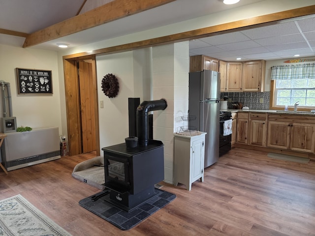 25 Oak Ridge Rd, Shirley, ME 04485 - kitchen featuring gas stove, freestanding refrigerator, a sink, light wood finished floors, and a wood stove