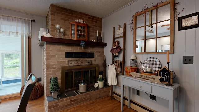 76 Parkview Ave, Livermore Falls, ME 04254 - living area featuring wood finished floors, ornamental molding, a brick fireplace, and a textured ceiling