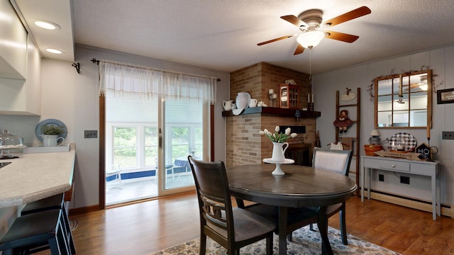 76 Parkview Ave, Livermore Falls, ME 04254 - dining space featuring wood finished floors, a ceiling fan, a textured ceiling, a fireplace, and recessed lighting