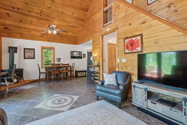 80 Hart St, Newport, ME 04953 - living room with ceiling fan, wood walls, a wood stove, stone finish flooring, and high vaulted ceiling