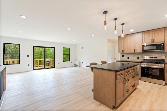 734 Main Rd, Charleston, ME 04422 - kitchen featuring appliances with stainless steel finishes, open floor plan, light wood-type flooring, decorative backsplash, and a center island