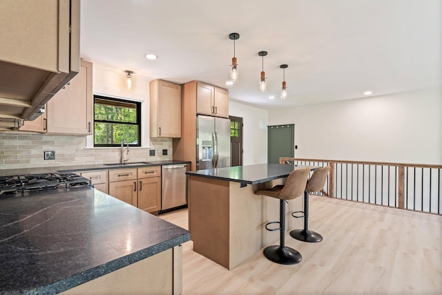 734 Main Rd, Charleston, ME 04422 - kitchen with stainless steel appliances, dark countertops, light wood-style flooring, backsplash, and a kitchen breakfast bar