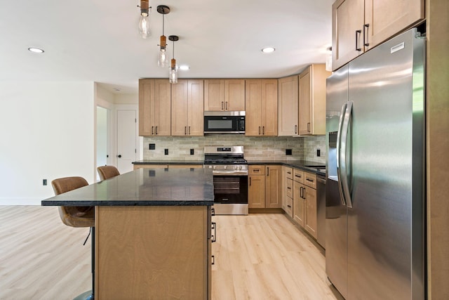 734 Main Rd, Charleston, ME 04422 - kitchen with stainless steel appliances, light wood-type flooring, a kitchen bar, a kitchen island, and backsplash