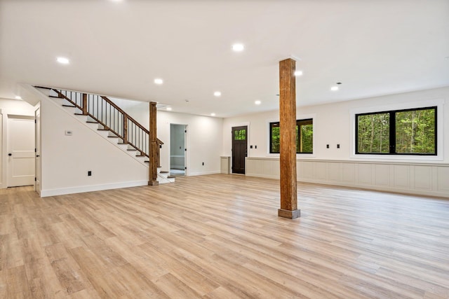 734 Main Rd, Charleston, ME 04422 - unfurnished living room with ornate columns, light wood-style flooring, stairway, recessed lighting, and wainscoting