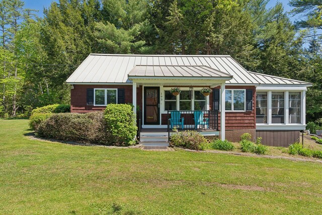 193 Park Ln, Windsor, ME 04363 - single story home featuring a standing seam roof, covered porch, a front lawn, metal roof, and a sunroom