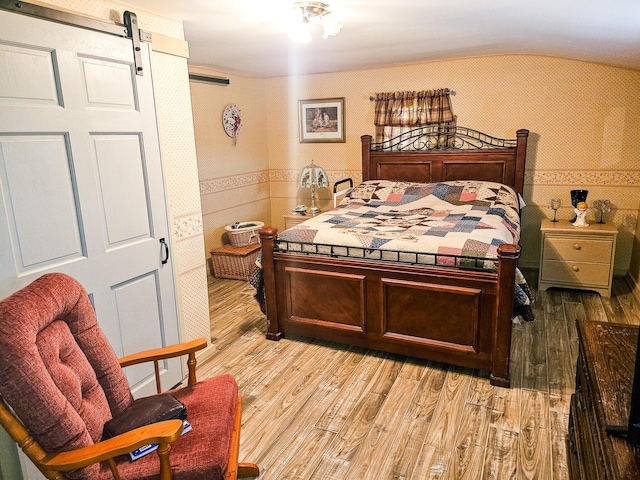 856 Weeks Mills Rd, New Sharon, ME 04955 - bedroom featuring a barn door, lofted ceiling, light wood finished floors, a wainscoted wall, and tile walls