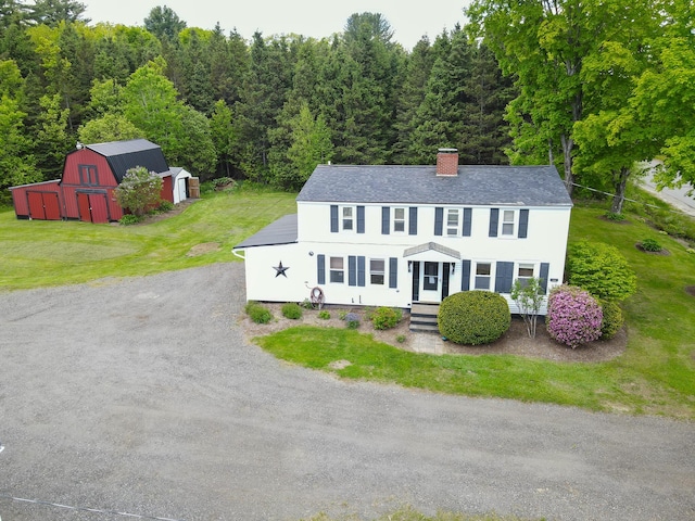 856 Weeks Mills Rd, New Sharon, ME 04955 - colonial-style house with a chimney, an outbuilding, a view of trees, a front yard, and driveway