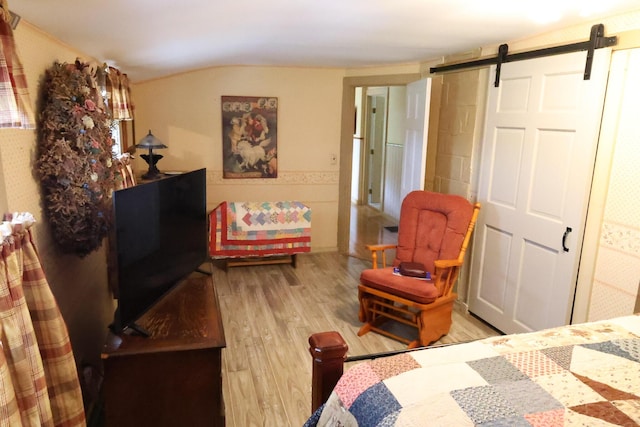 856 Weeks Mills Rd, New Sharon, ME 04955 - bedroom with wood finished floors, a barn door, and vaulted ceiling