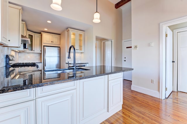 99 Silver St Unit 3-10, Portland, ME 04101 - kitchen featuring freestanding refrigerator, baseboards, a peninsula, backsplash, and glass insert cabinets