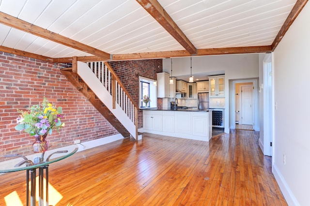 99 Silver St Unit 3-10, Portland, ME 04101 - unfurnished living room with stairs, baseboards, light wood-style flooring, brick wall, and a sink