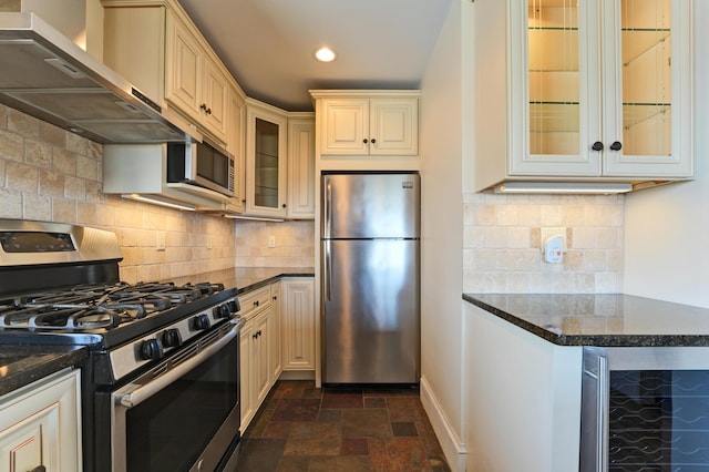 99 Silver St Unit 3-10, Portland, ME 04101 - kitchen with stainless steel appliances, cream cabinetry, wine cooler, wall chimney exhaust hood, and dark stone finish floors
