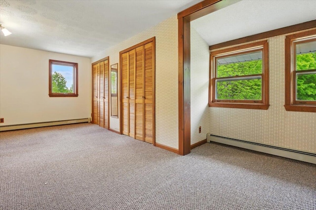 473 Davenport Hill Rd, Jay, ME 04239 - unfurnished bedroom featuring multiple closets, a baseboard radiator, a baseboard heating unit, carpet, and wallpapered walls