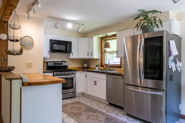 1007 Old Stage Rd, Woolwich, ME 04579 - kitchen featuring stainless steel appliances, a sink, butcher block countertops, white cabinets, and a peninsula
