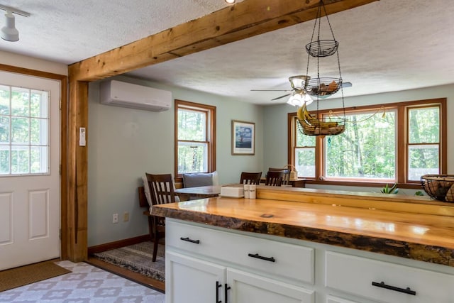 1007 Old Stage Rd, Woolwich, ME 04579 - kitchen with a wall mounted AC, wooden counters, a textured ceiling, white cabinetry, and a ceiling fan
