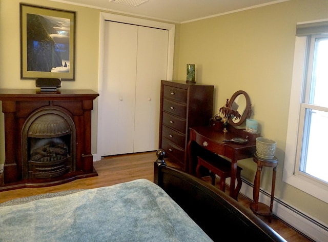 27 Misty Harbor Ln Unit 210, Cutler, ME 04626 - bedroom featuring wood finished floors, a closet, crown molding, and a fireplace with raised hearth
