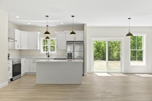 25 Sarah Vaughn Rd, Hollis, ME 04042 - kitchen with appliances with stainless steel finishes, a center island, light countertops, light wood-style flooring, and white cabinets