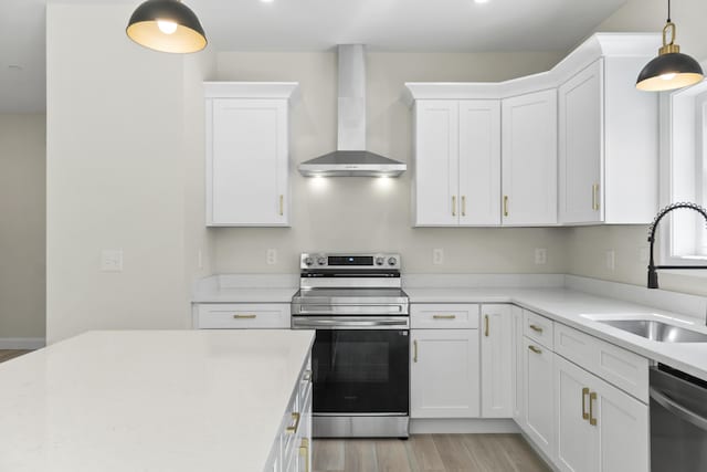 25 Sarah Vaughn Rd, Hollis, ME 04042 - kitchen featuring stainless steel appliances, wall chimney range hood, a sink, light wood finished floors, and white cabinetry