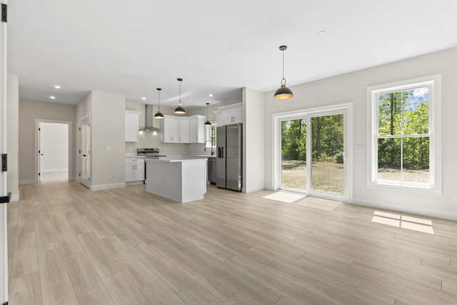 25 Sarah Vaughn Rd, Hollis, ME 04042 - kitchen with wall chimney range hood, stainless steel appliances, a center island, light countertops, and light wood-type flooring