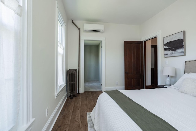 205 Beach St, Saco, ME 04072 - bedroom featuring a wall mounted AC, radiator heating unit, dark wood finished floors, baseboards, and multiple windows