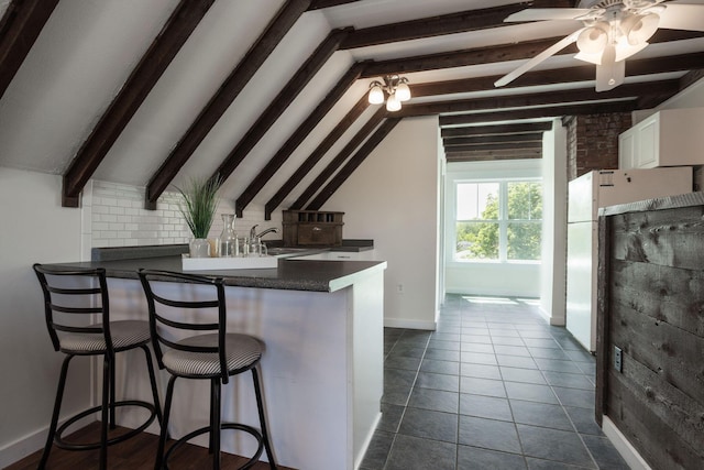 205 Beach St, Saco, ME 04072 - kitchen featuring white cabinetry, a peninsula, dark countertops, a breakfast bar, and baseboards