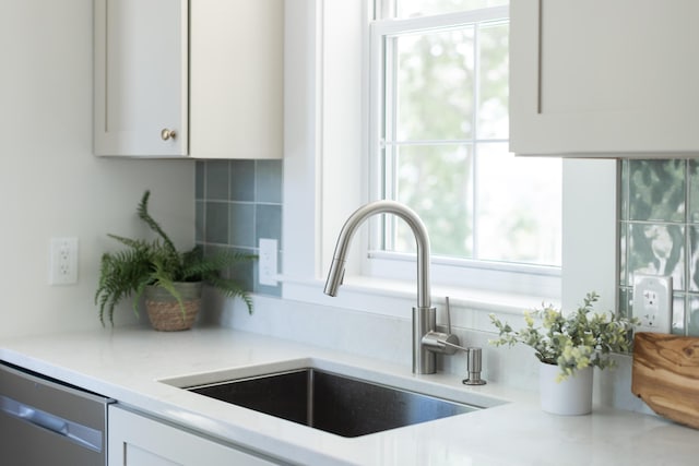 205 Beach St, Saco, ME 04072 - kitchen view of a sink, stainless steel dishwasher, white cabinetry, and tasteful backsplash