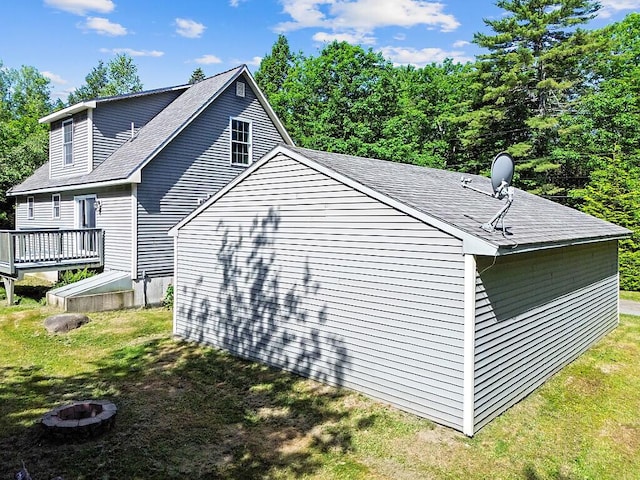 40 Guptill Rd, Belgrade, ME 04917 - view of property exterior featuring a deck, roof with shingles, a lawn, and a fire pit