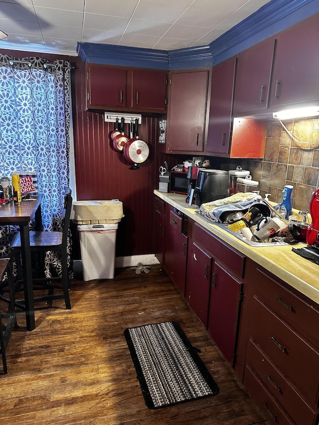 33 Washington St, Caribou, ME 04736 - kitchen featuring light countertops, black microwave, dark wood-style flooring, decorative backsplash, and crown molding