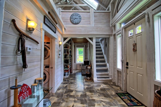 14 Jude Ln, Ellsworth, ME 04605 - entryway featuring stacked washer / dryer, wood walls, high vaulted ceiling, and stairway