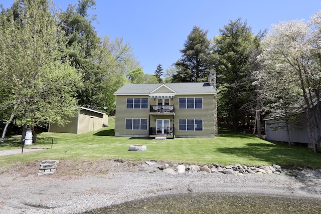 500 Black Point Rd, Beaver Cove, ME 04441 - view of front of house with a chimney, a front lawn, an outbuilding, and french doors