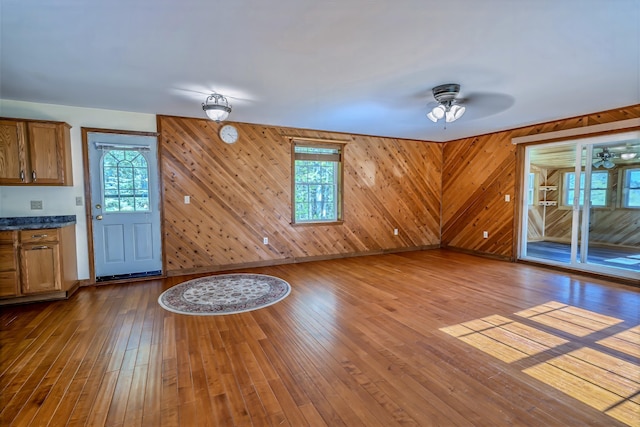 3 Reeds Ln, Belfast, ME 04915 - unfurnished living room featuring a ceiling fan, hardwood / wood-style floors, baseboards, and wood walls