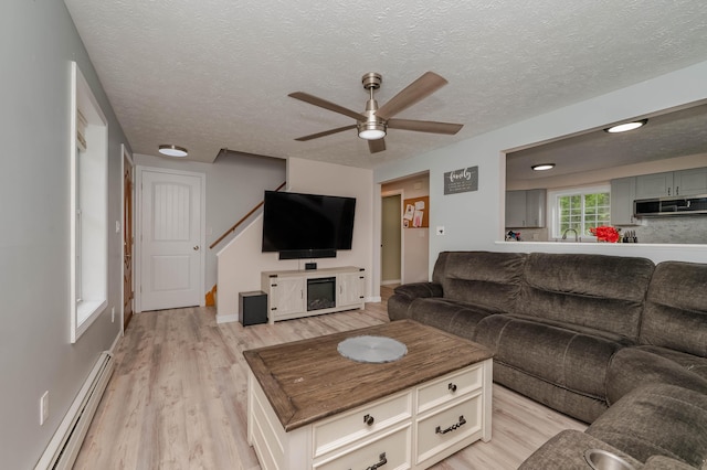 68 Lone Pine Rd, Waterboro, ME 04061 - living room with a baseboard heating unit, a ceiling fan, light wood-style floors, a textured ceiling, and baseboards