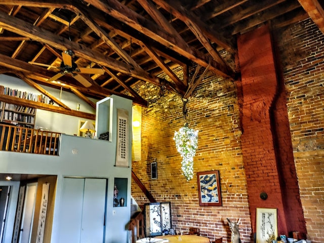 92-94 Main St, Auburn, ME 04210 - unfurnished living room featuring high vaulted ceiling, ceiling fan, brick wall, a wood stove, and beam ceiling