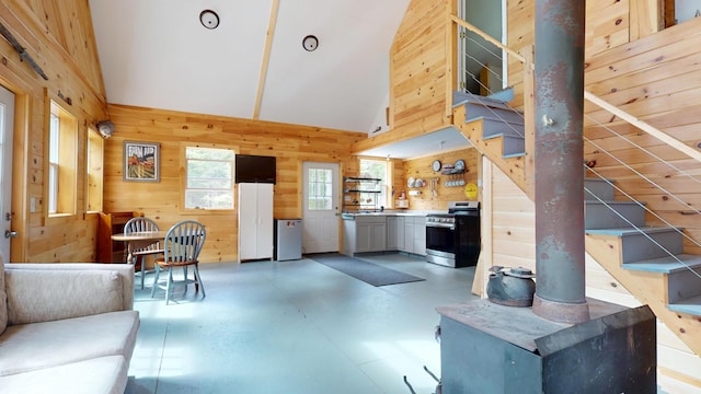 121 Loop Rd, Lincoln, ME 04457 - living area with wood walls, concrete flooring, high vaulted ceiling, and stairs