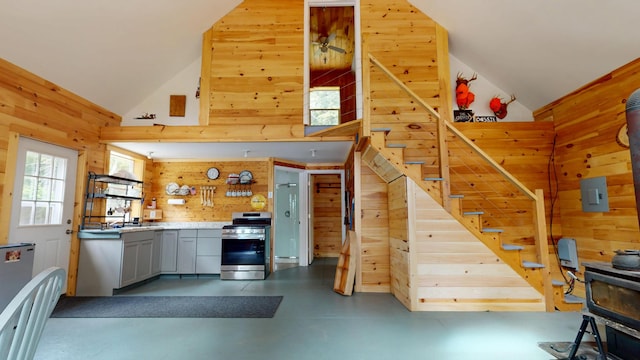 121 Loop Rd, Lincoln, ME 04457 - kitchen featuring stainless steel range with gas stovetop, wood walls, high vaulted ceiling, gray cabinetry, and finished concrete floors