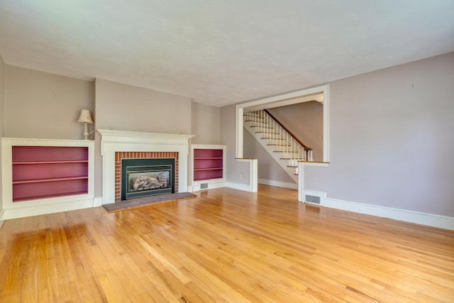 61 Carlyle Rd, Portland, ME 04103 - unfurnished living room featuring stairway, a fireplace, wood finished floors, and baseboards