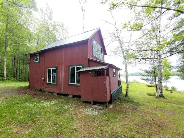 16 Mellen Ln, Wilton, ME 04294 - view of home's exterior with metal roof, an outbuilding, a lawn, and a water view
