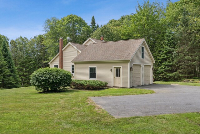 61 Crestview Ln, Brunswick, ME 04011 - view of home's exterior with a chimney, roof with shingles, a lawn, and a detached garage