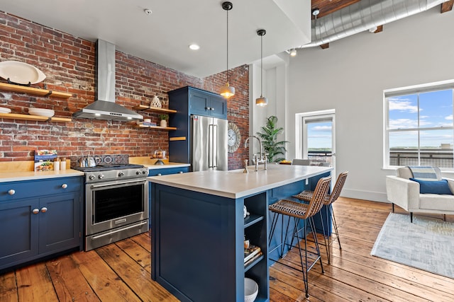 15 Brown St Unit 405, Portland, ME 04101 - kitchen with open shelves, appliances with stainless steel finishes, blue cabinetry, wall chimney exhaust hood, and brick wall