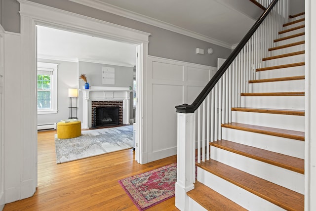 797 Main St, South Portland, ME 04106 - staircase with baseboard heating, wood finished floors, ornamental molding, a decorative wall, and a fireplace