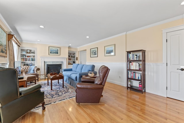 14 Merriconeag Ln, Harpswell, ME 04079 - living area featuring a glass covered fireplace, light wood-style flooring, a wainscoted wall, ornamental molding, and built in features