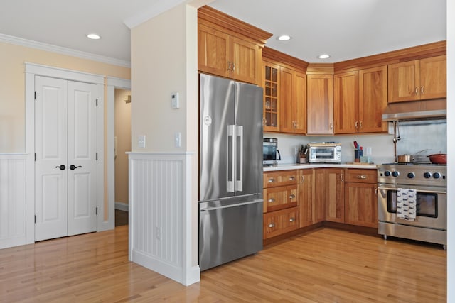 14 Merriconeag Ln, Harpswell, ME 04079 - kitchen with stainless steel appliances, under cabinet range hood, brown cabinetry, ornamental molding, and light countertops