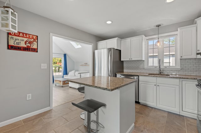 27 Seaside Ave, Saco, ME 04072 - kitchen featuring stainless steel appliances, a skylight, tasteful backsplash, stone counters, and white cabinets