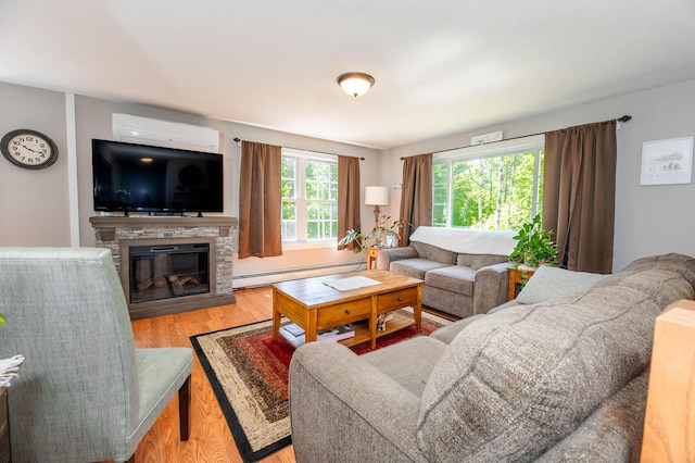 77 Toothaker Pond Rd, Phillips, ME 04966 - living area with a baseboard heating unit, a wall mounted AC, wood finished floors, and a stone fireplace