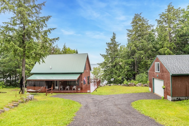 32 Sandy Beach Rd, Danforth, ME 04424 - chalet / cabin featuring a garage, covered porch, a front lawn, an outbuilding, and asphalt driveway
