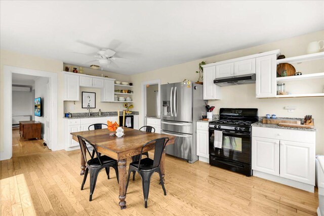 276 N Sedgwick Rd, Sedgwick, ME 04676 - kitchen with black gas range, stainless steel fridge, open shelves, under cabinet range hood, and light wood-style floors
